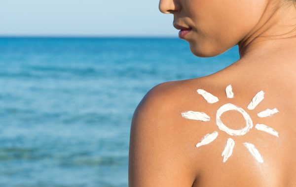 Woman With Suntan Lotion At The Beach In Form Of The Sun