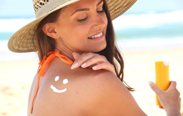 Woman sat on the beach applying sun cream